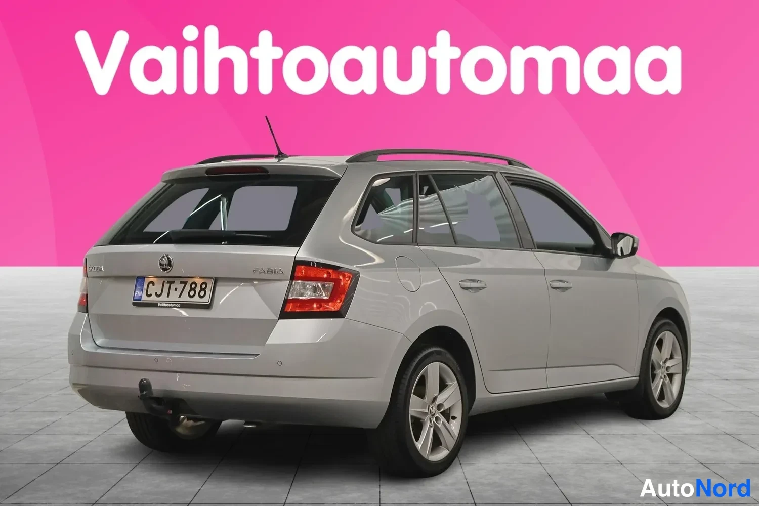 Takaviisto: Auton takaosa ja vasen kylki kolmeneljäsosakulmasta, hopeinen farmarikorinen auto rekisterikilpi, kattokaiteet ja perilaissekoitin näkyvät.