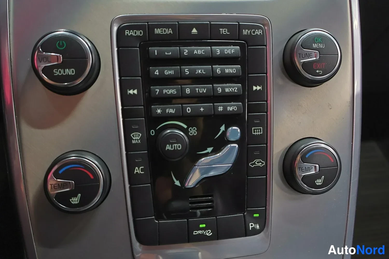 Yksityiskohta: Autohallintapaneeli: radio- ja mediasäätimet, numeronäppäimet ja kaksialueinen automaattilämmitin nuppeineen.
