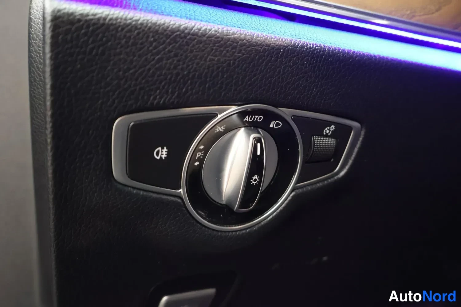 Muu: Sisätilakuvan lähikuva auton valokytkimestä, jossa AUTO-merkintä ja sumuvalojen painike.