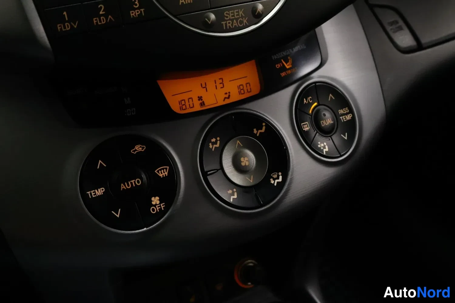 Muu: Auton kojelautaan kiinnitetty automaattinen ilmastointipaneeli: TEMP ja AUTO -säätimet, keskellä puhallinsäädin ja oikealla A/C- ja DUAL/PASS TEMP -nappi. Orans