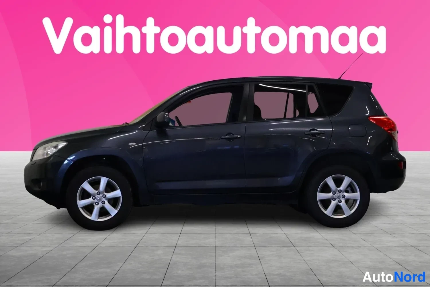 Takaviisto: Toyota RAV4 sivuprofiilista vasemmalta, tummansininen kori, hopeanväriset kevytmetallivanteet.