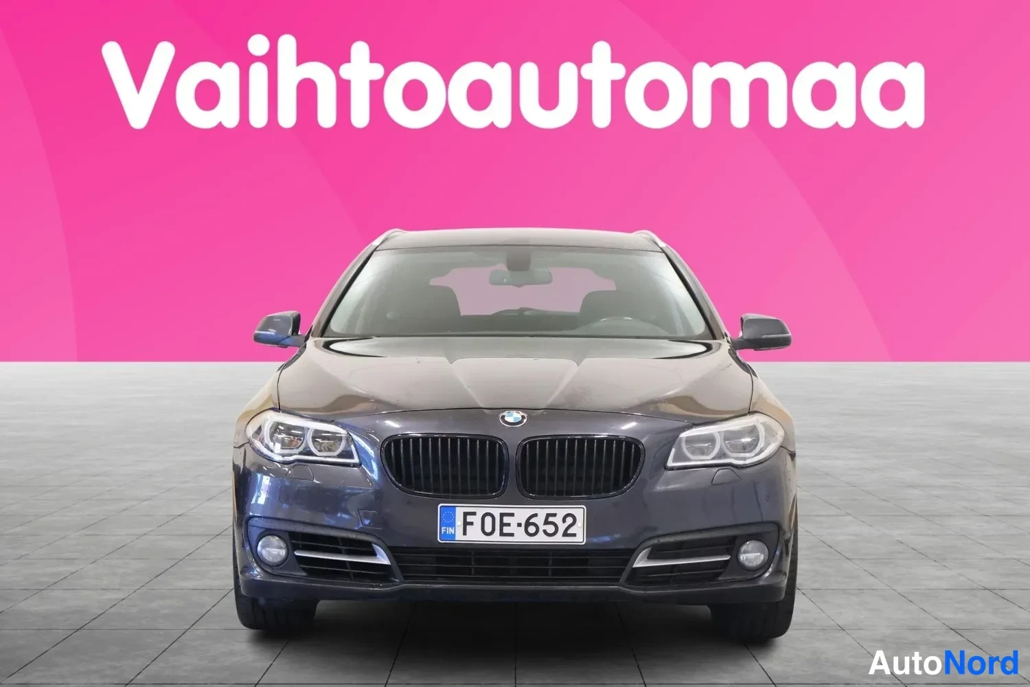 Edestä: Tummanharmaa henkilöauto suoraan edestä kuvattuna, rekisteritunnus.