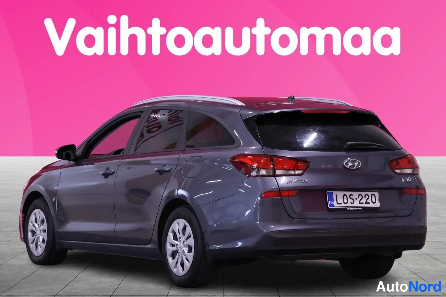 Takaviisto: Tummanharmaa Hyundai i30 -farmari takakulmasta vasemmalta kuvattuna: näkyvät takavalot, Hyundai-tähti ja i30-merkki, rekisterikilpi sekä kattokaiteet.