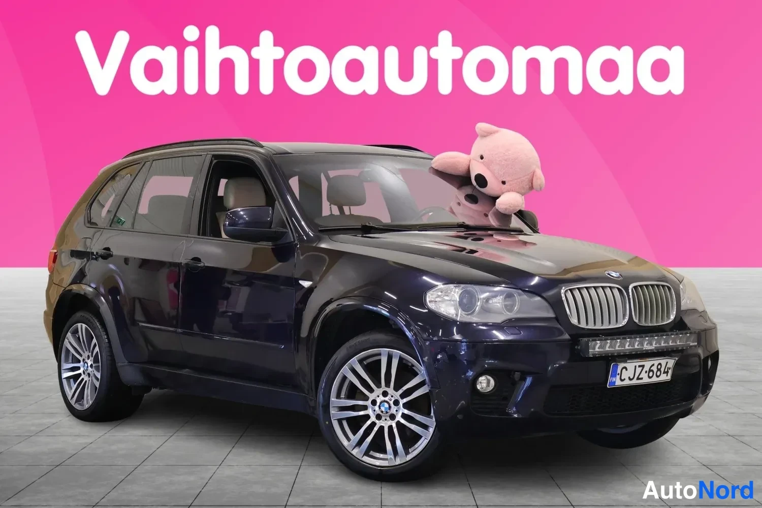 Etuviisto, nokka oikealle: Tumma BMW X5 -maastokuorma-auto kuvattu kolmavärisestä etunäkymästä, keula ja vasen kylki näkyvissä.