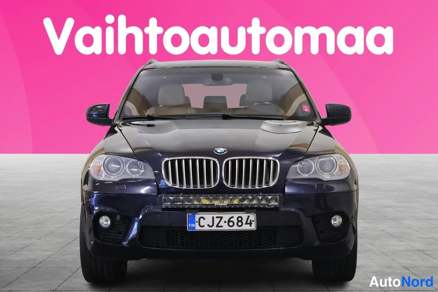 Edestä: BMW X5:n keula suoraan edestäpäin; etusäleikkö, ajovalot ja rekisterikilpi näkyvissä.
