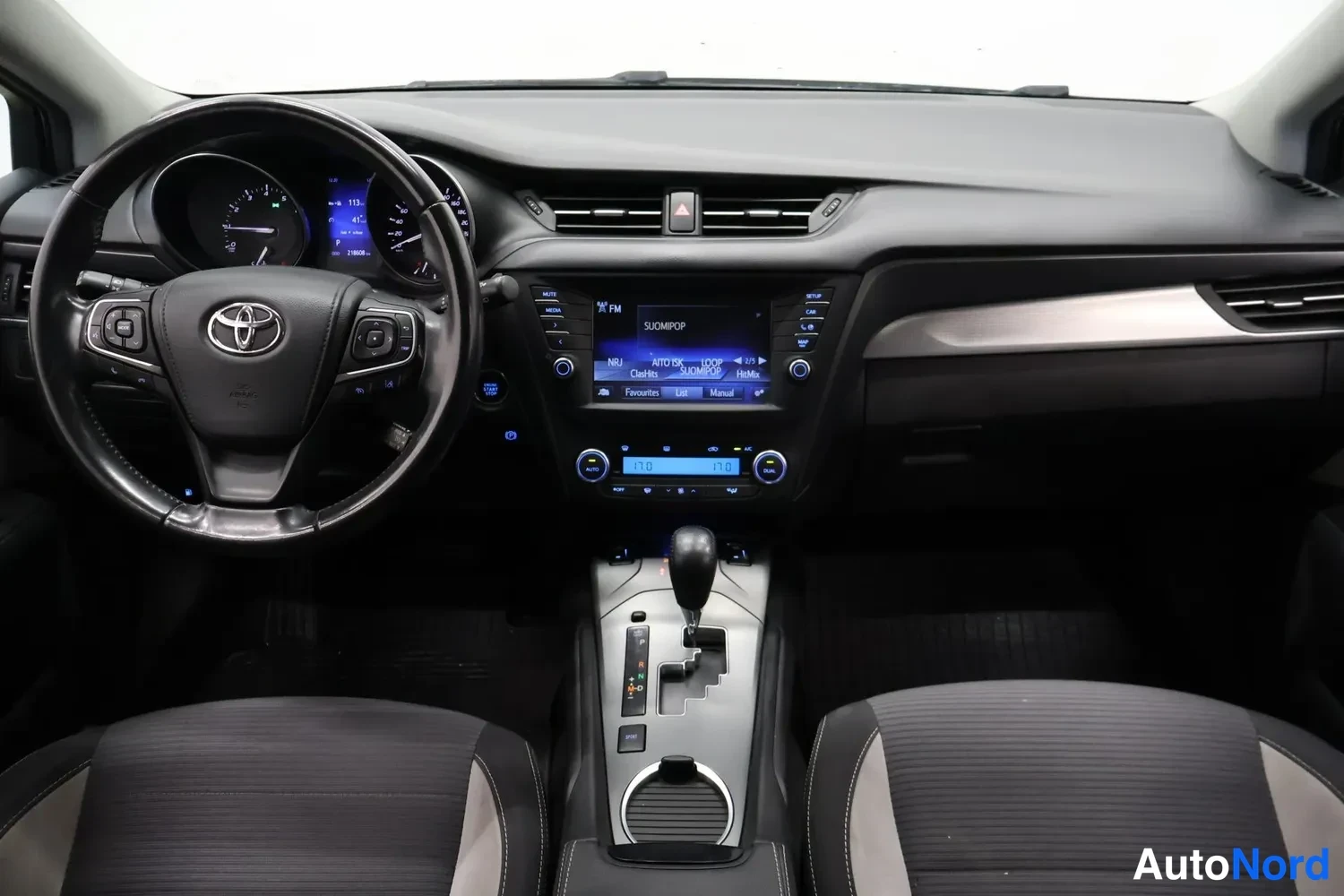 Muu: Koko kojelauta keskeltä: Toyota-ohjauspyörä, keskellä infotainment- ja ilmastointilaitteiden näytöt ja napit, automaattivaihteiston valitsin ja kaksi etuistuint