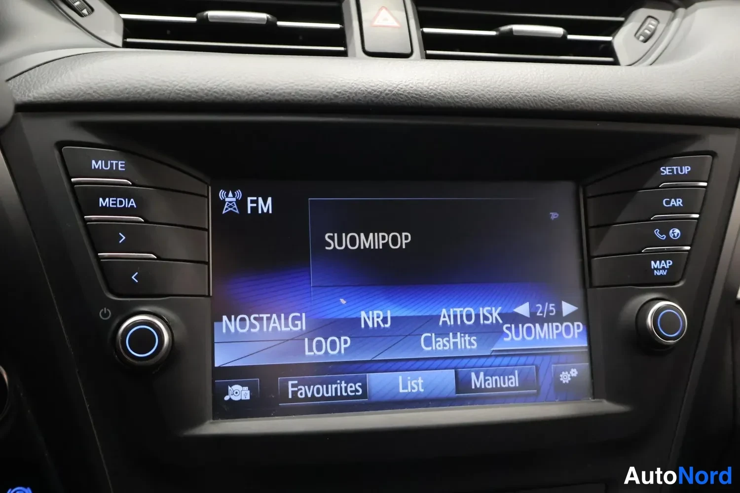 Muu: Auton infotainment-näyttö näyttää FM-radiota ja valittuna on asema SuomiPop; näytöllä näkyvät myös NostalgI, NRJ, Aito Isk, Loop ja ClasHits, ja alapuolella Fav