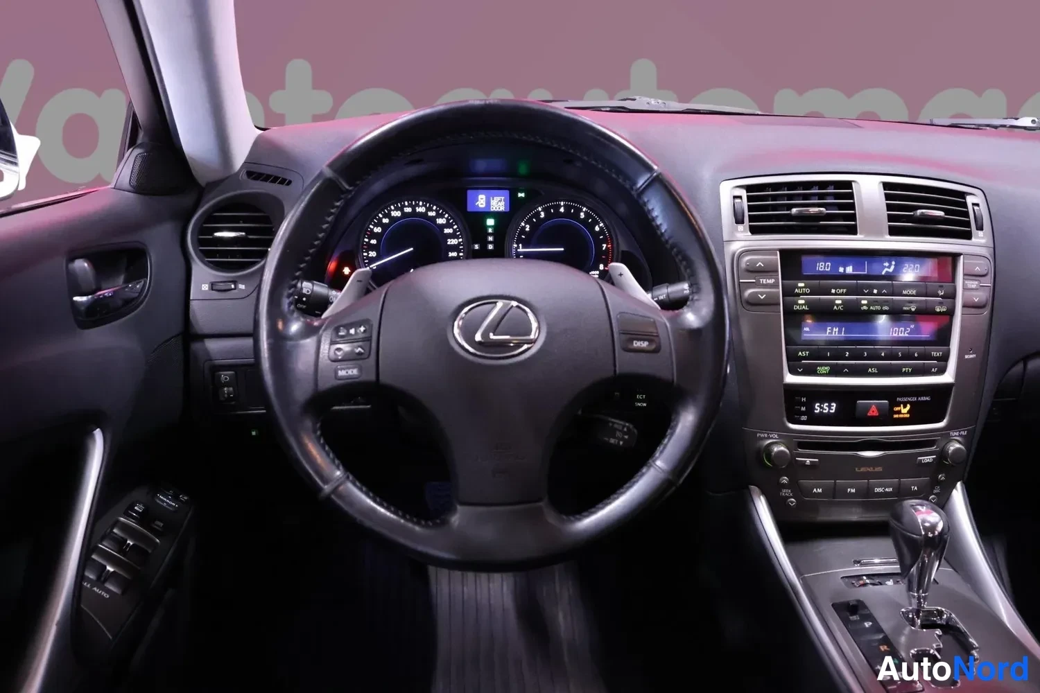 Yksityiskohta: Ohjaamon etunäkymä Lexus-ohjauspyörällä, mittaristolla ja keskikonsolin infotainmenlyksydillä ja vaihtajanuppeilla.