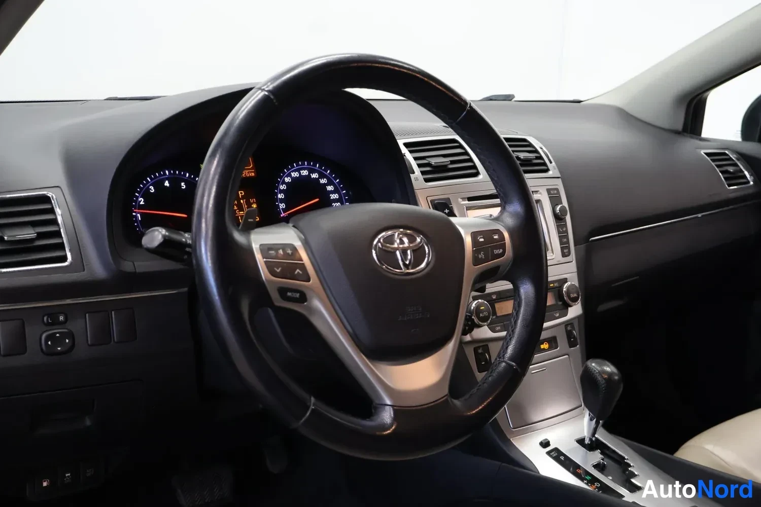 Yksityiskohta: Kuljettajan näkymä: Toyota-ohjauspyörä, mittaristo ja automaattivaihteiston valitsin, kojetaulun ruutu ja ilmastointiaukot.