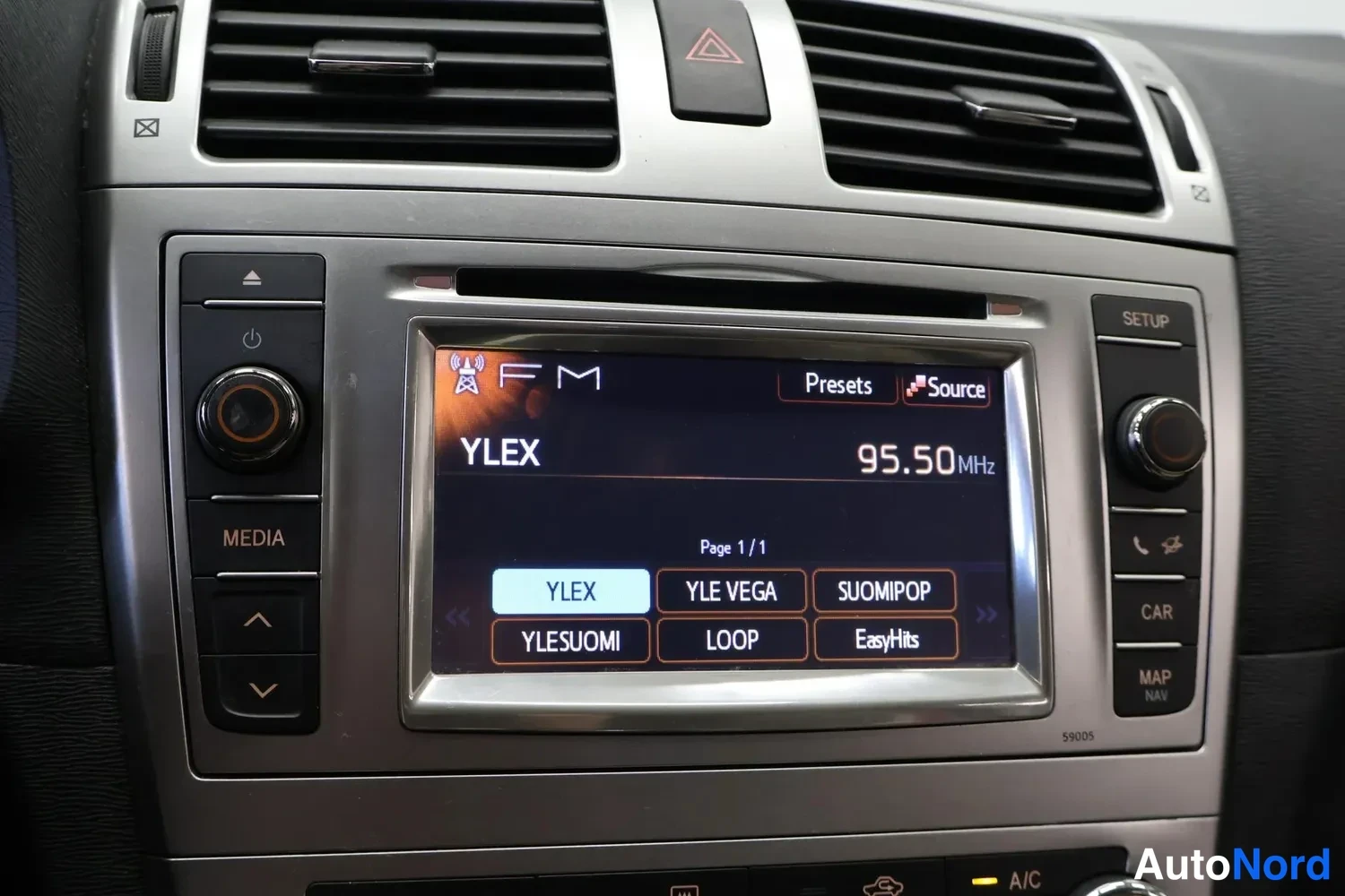 Muu: Kojelaudan radiopaneelin lähikuva: kosketusnäytöllä FM-radio kanavalla 95.50 MHz, asema YLEX, esivalittuja asemia YLEX, YLE VEGA, SUOMIPOP, YLESUOMI, LOOP ja Ea
