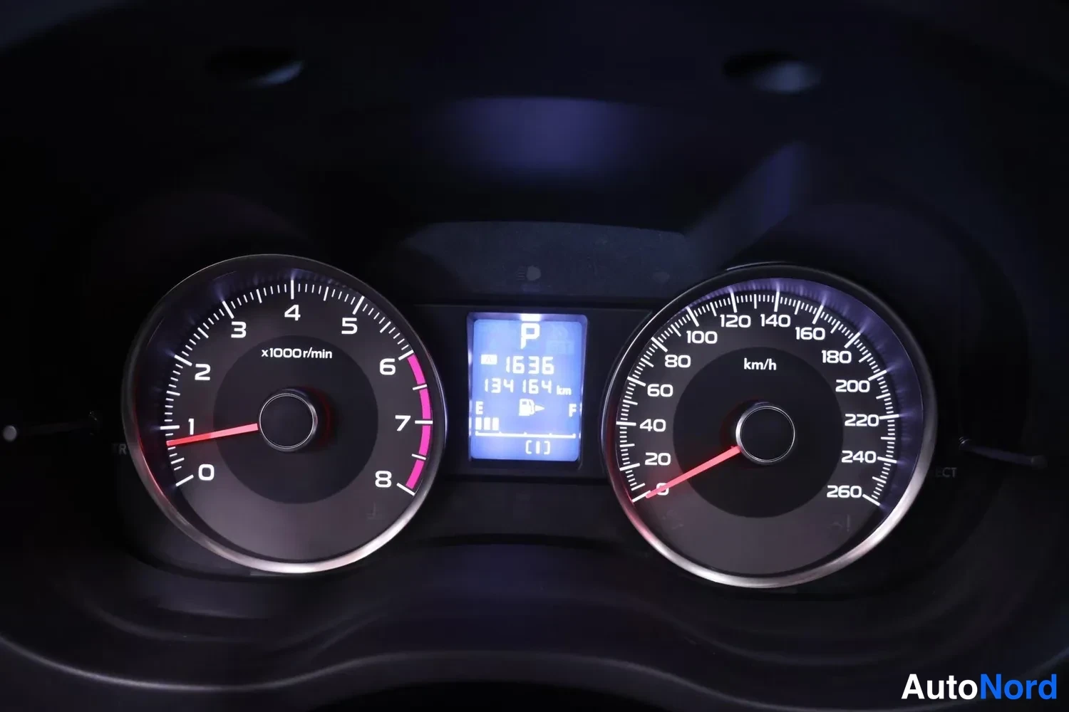 Yksityiskohta: Nearkuva mittaristosta: kierroslukumittari ja nopeusmittari, näytössä P-vaihde ja lukema 134 164 km.