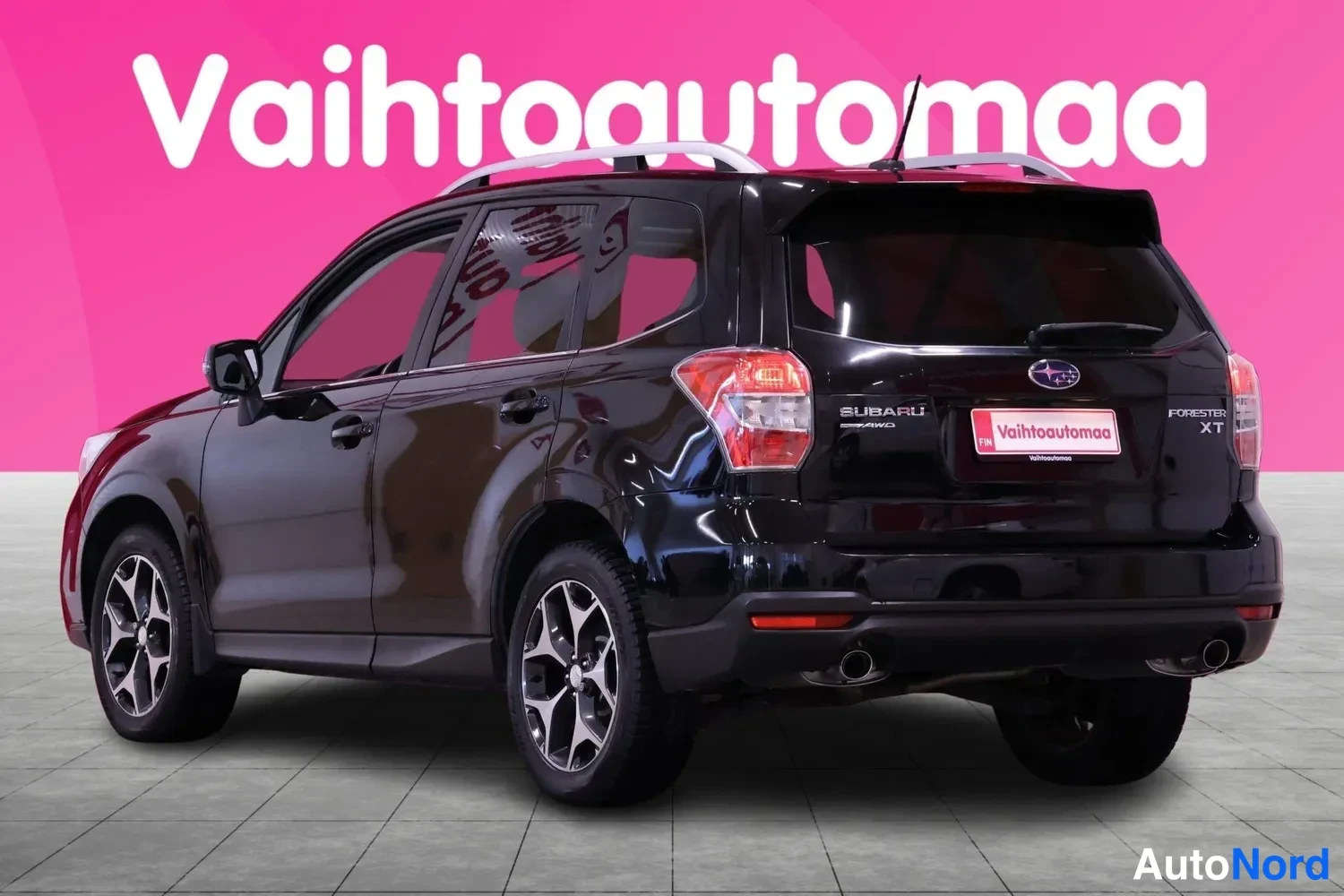 Takaviisto: Musta Subaru Forester kuvattuna takaa viistosti: takavalot, takaluukku ja auton kylki ovineen ja pyörineen näkyvät, päällä hopeiset kattokaiteet.