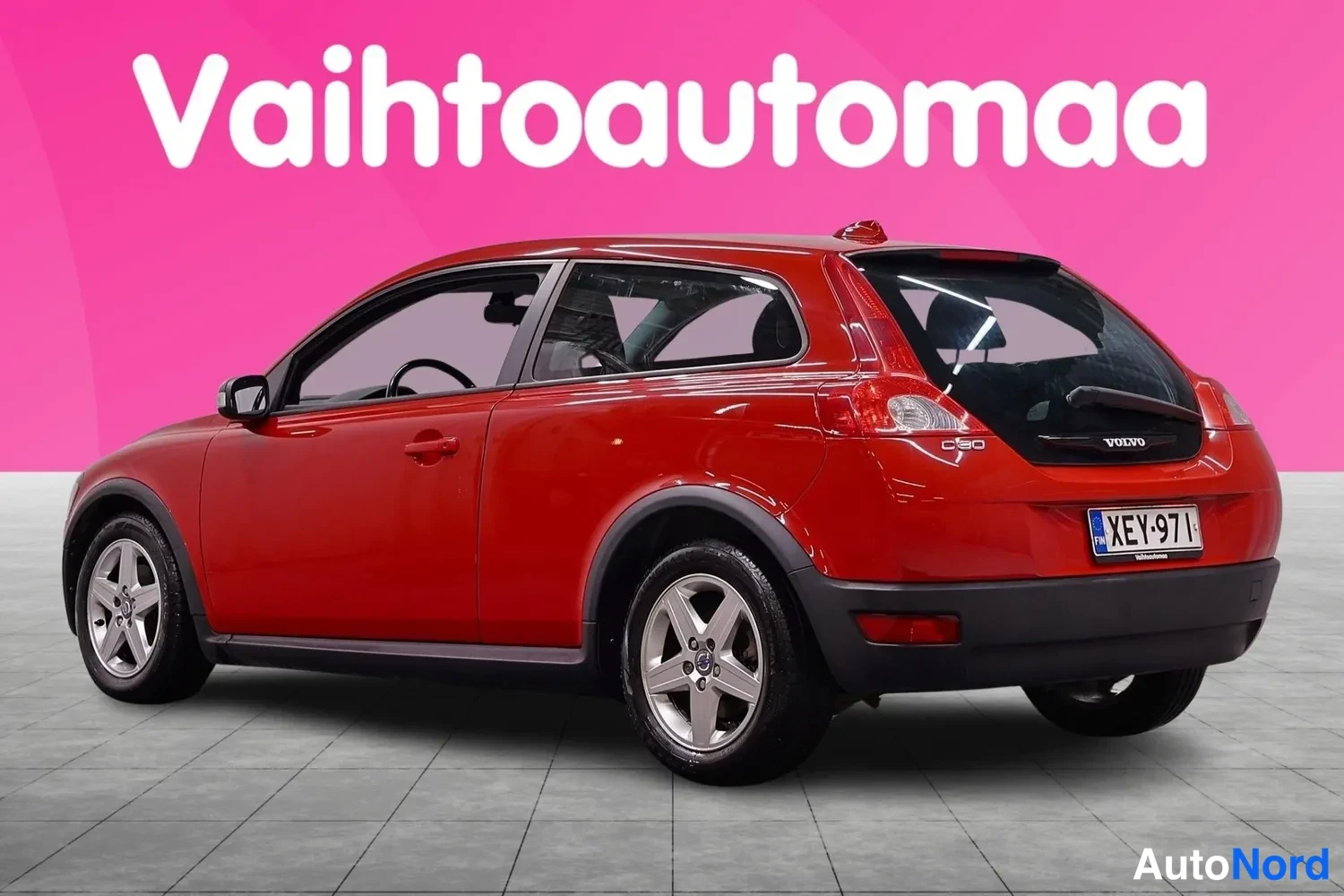 Takaviisto: Punainen auton takaosa kolmionneljänneskulmasta, takaluukussa Volvo-merkki, rekisterikilpi.