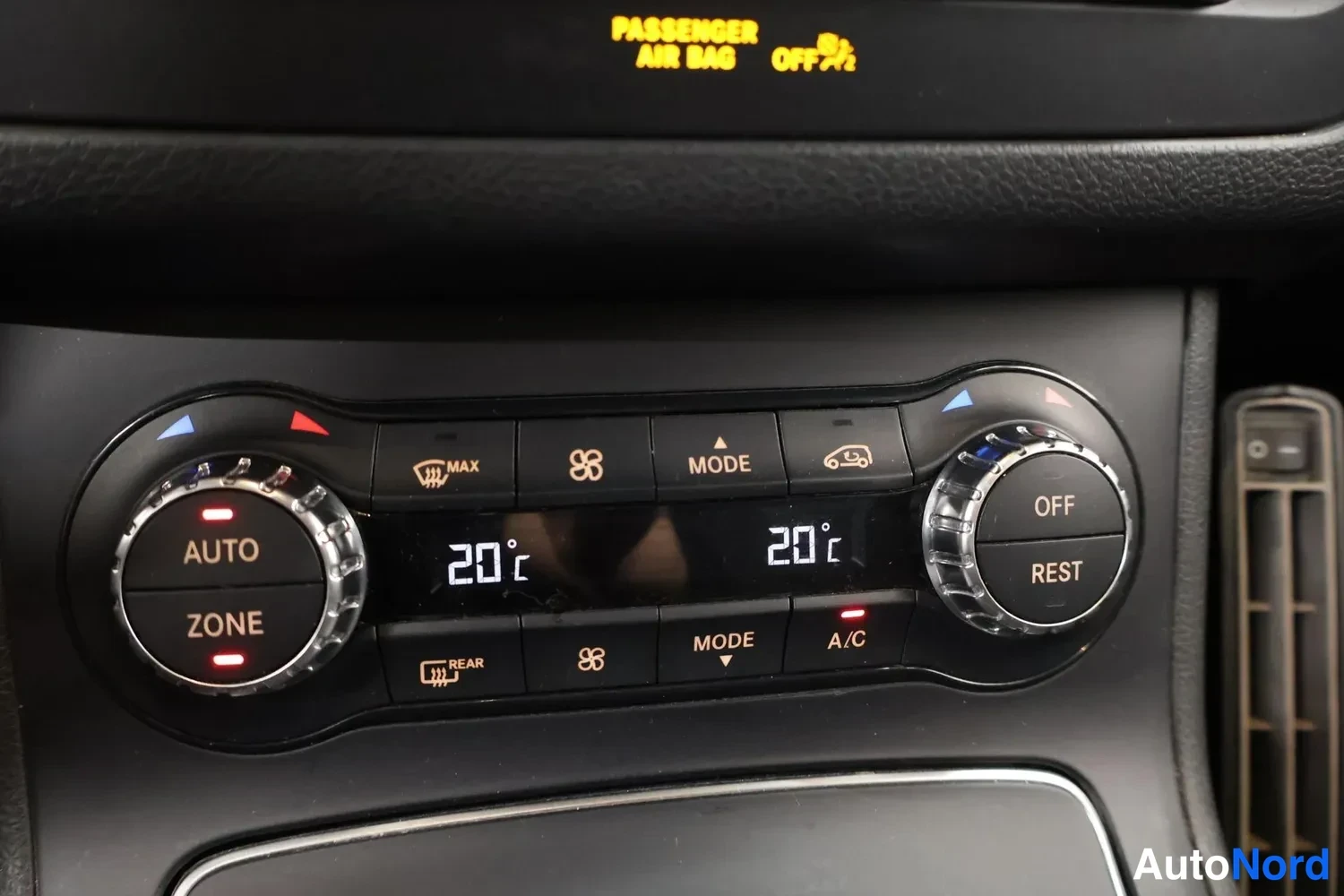 Yksityiskohta: Automaattinen kaksivyöhykeilmastointi: näytössä 20 °C molemmilla puolilla, napit AUTO, ZONE, A/C, REST ja OFF; ylhäällä matkustajanturvatyynyn OFF-merkkivalo.