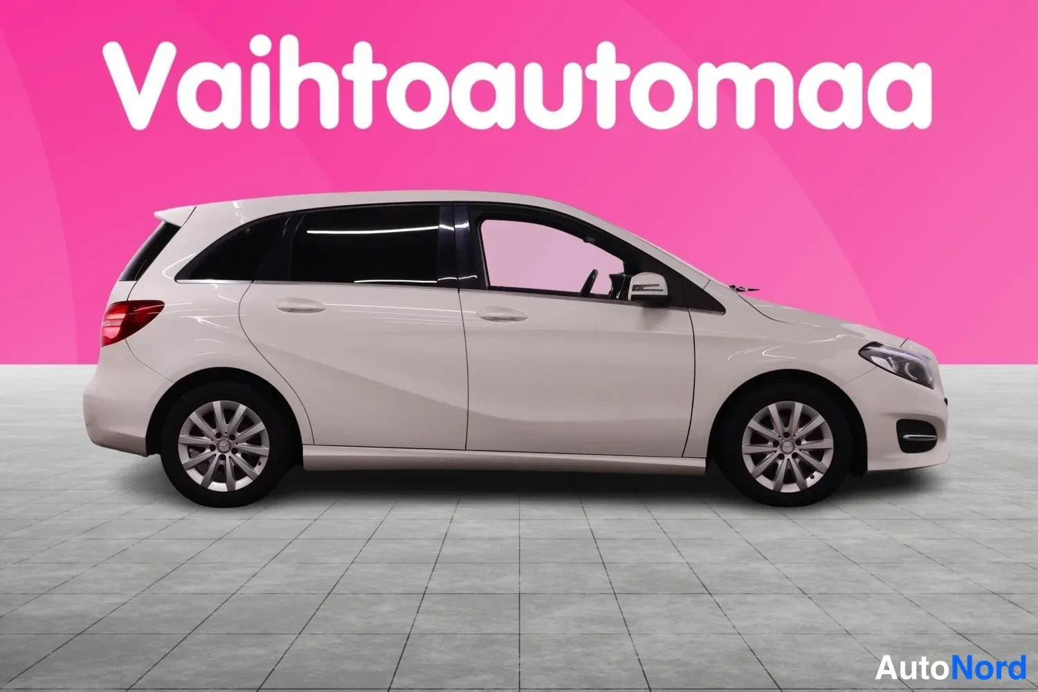 Etuviisto, nokka oikealle: Mercedes-Benz B:n kylki etukulmasta: valkoinen koripaneeli, ovien kahvat ja keulavalot, etupyörä kuvan oikeassa reunassa.