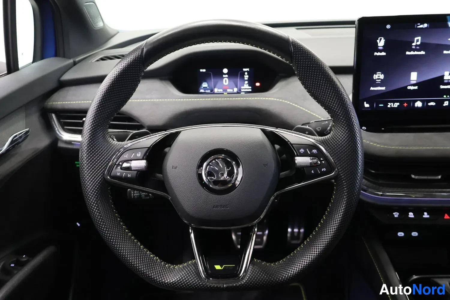 Muu: Ohjauspyörän lähikuva: Skoda-logolla varustettu suorakulmainen ohjauspyörä, digitaalinen mittaristo ja oikealla osa infotainment-näytöstä.