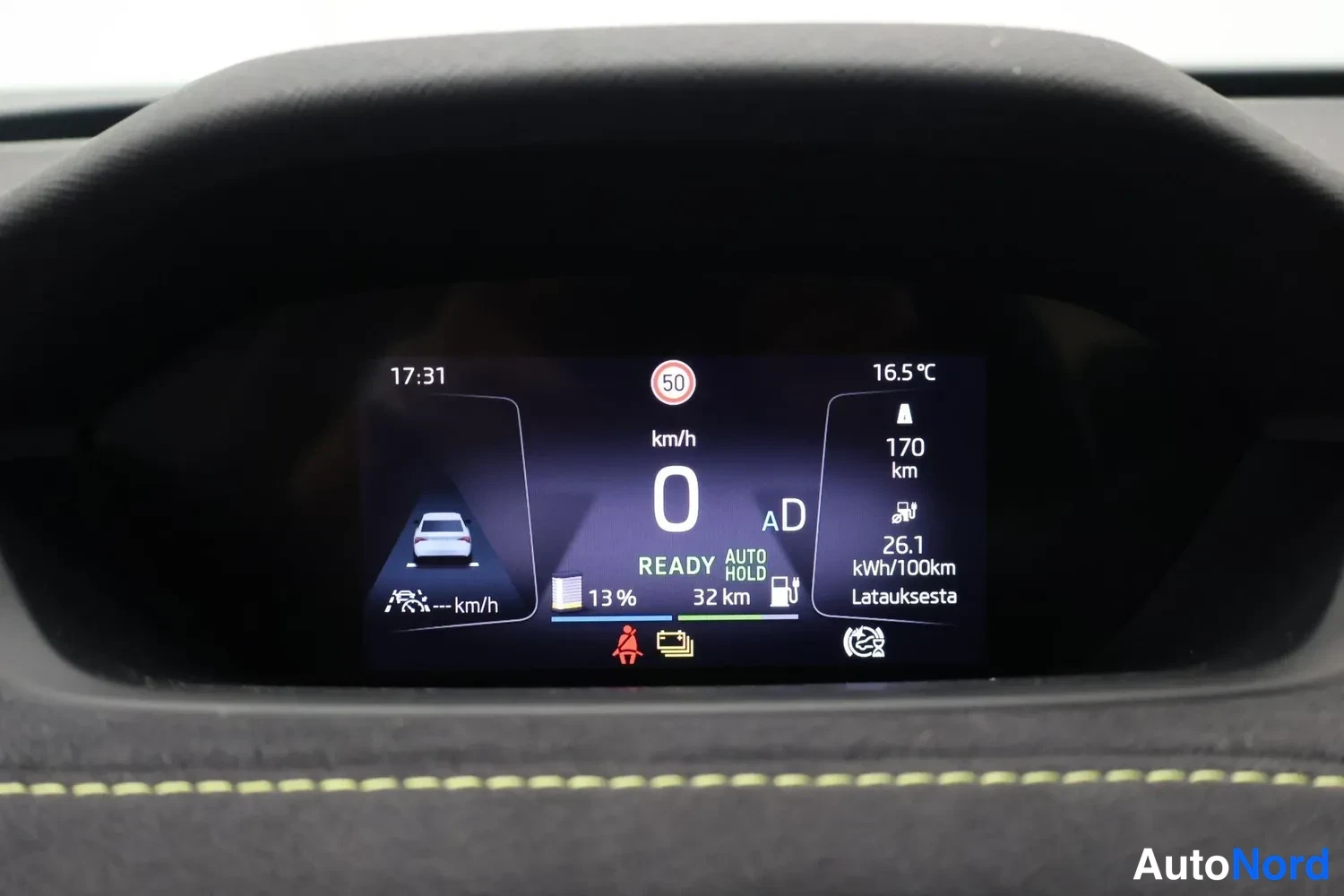 Yksityiskohta: Kuljettajan näytön lähikuva: nopeus 0 km/h, READY, jäännösakun varaustaso 13 %, toiminta-aika 32 km, toiminta-aikaan '170 km' ja kulutus 26,1 kWh/100km; Latauks