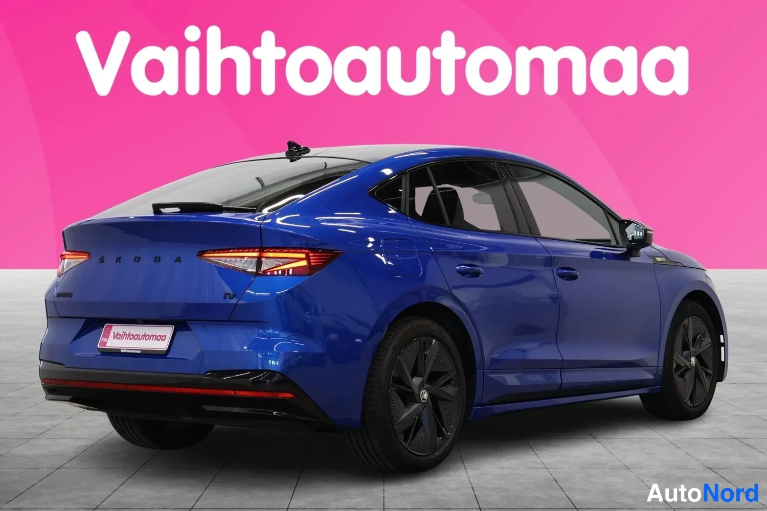 Takaviisto: Sininen SUV-coupé kuvattu takaa viistosti; rekisterikilven paikalla myyjän mainoskilpi, nokkamainen korimuotoilu ja tummat kevytmetallivanteet näkyvissä.