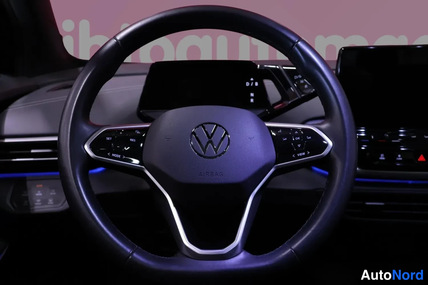 Muu: Volkswagenin ohjauspyörä lähikuvassa; ilmatyynymerkintä ja näppäimet (SET, RES, MODE, VIEW, OK).