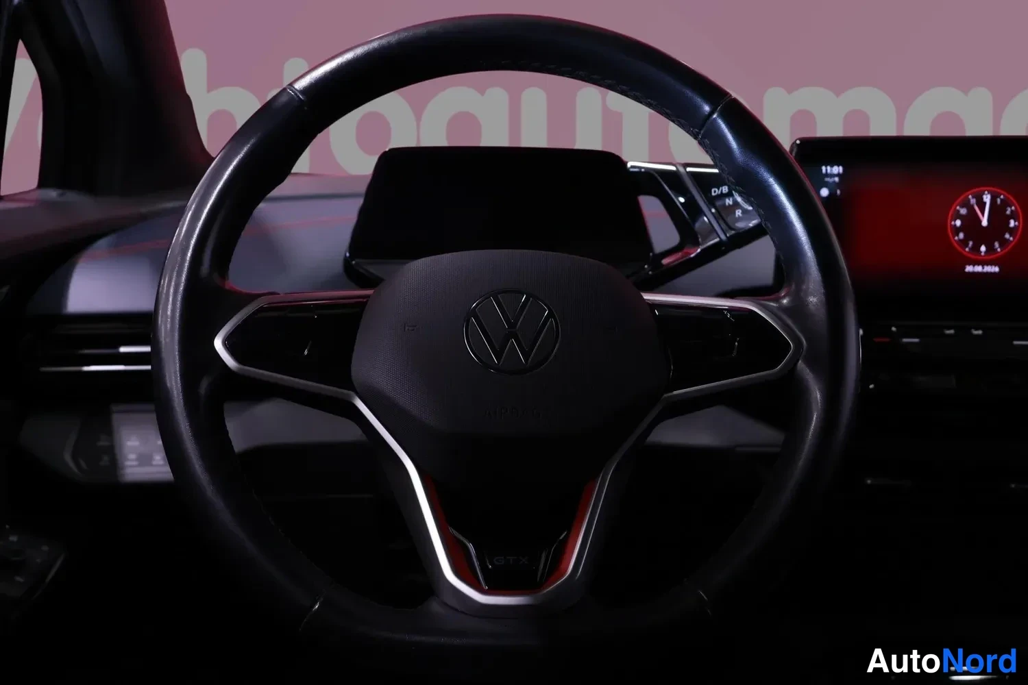 Muu: Ohjaamon näkymä: Volkswagen-ohjauspyörä, digitaalinen mittaristo ja keskinäyttö punaisella taustavaloisesti.