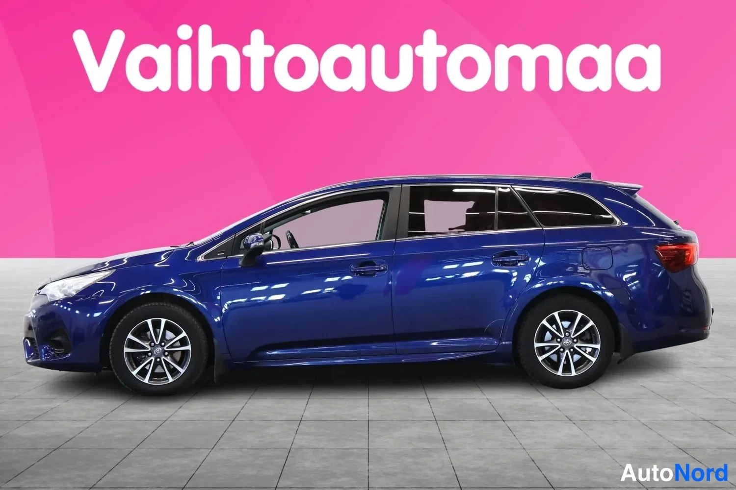 Sivulta: Sininen farmariauto sivusta vasemmalta katsottuna, vaaleanpunainen tausta.