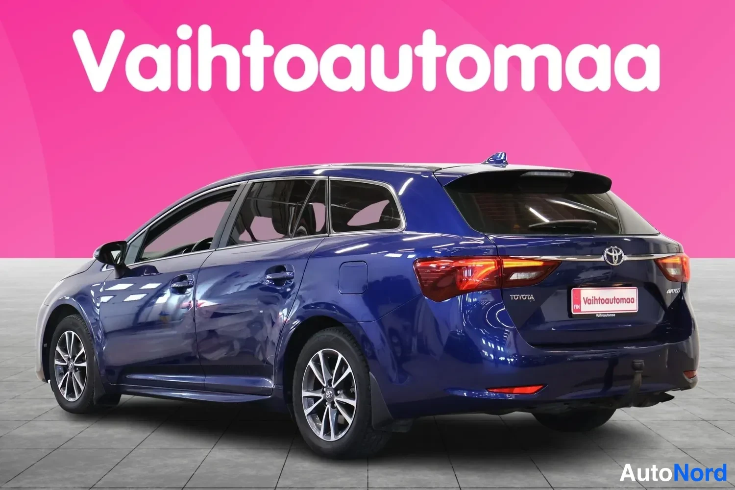 Takaviisto: Sininen farmariauto takaa oikealta kolmannespistettä katsottuna, takavalot ja Toyota-merkki näkyvissä.