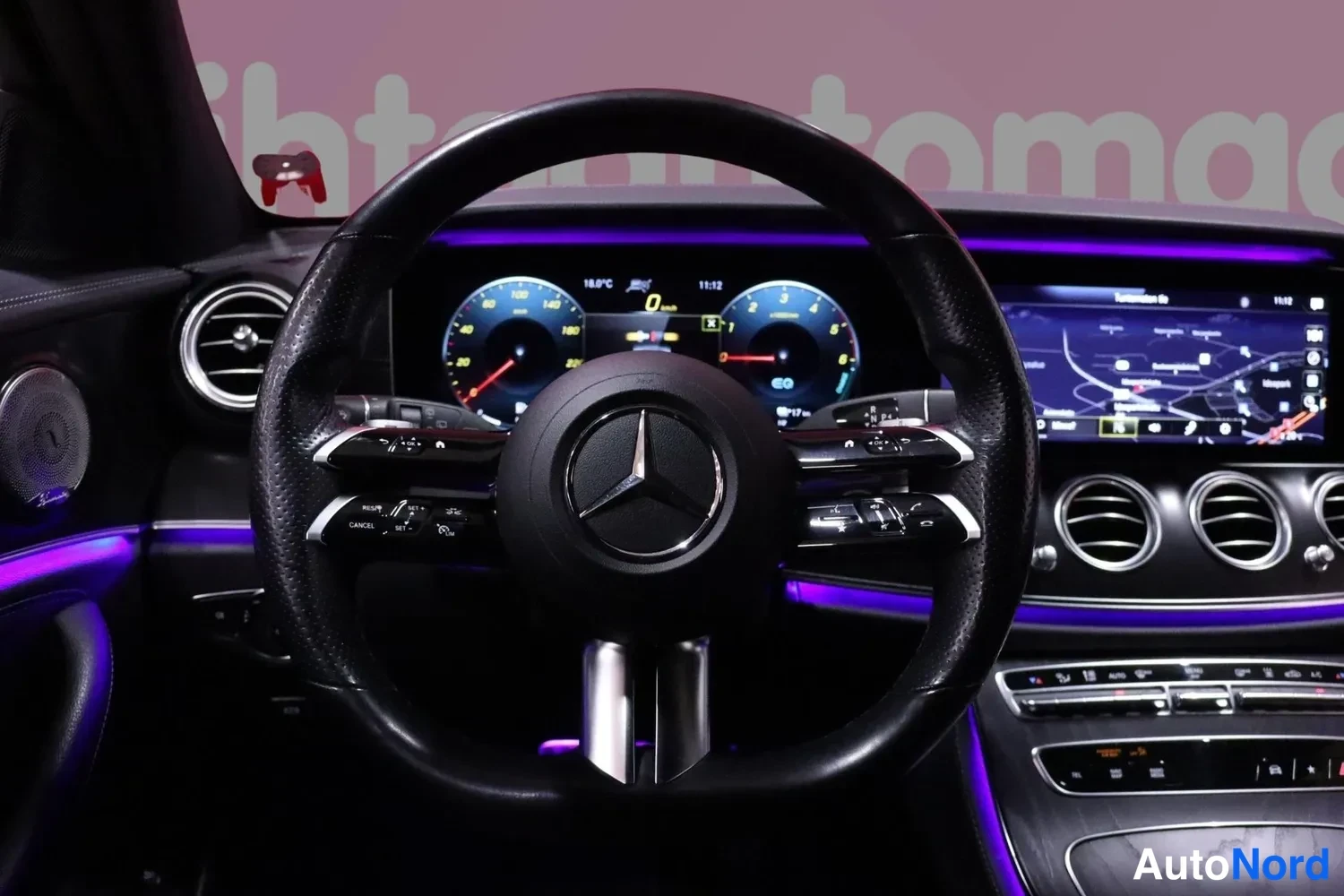 Yksityiskohta: Mercedes-ohjauspyörä ja digitaalinen mittaristo, karttanäyttö keskikonsolissa, nopeus 0 km/h.