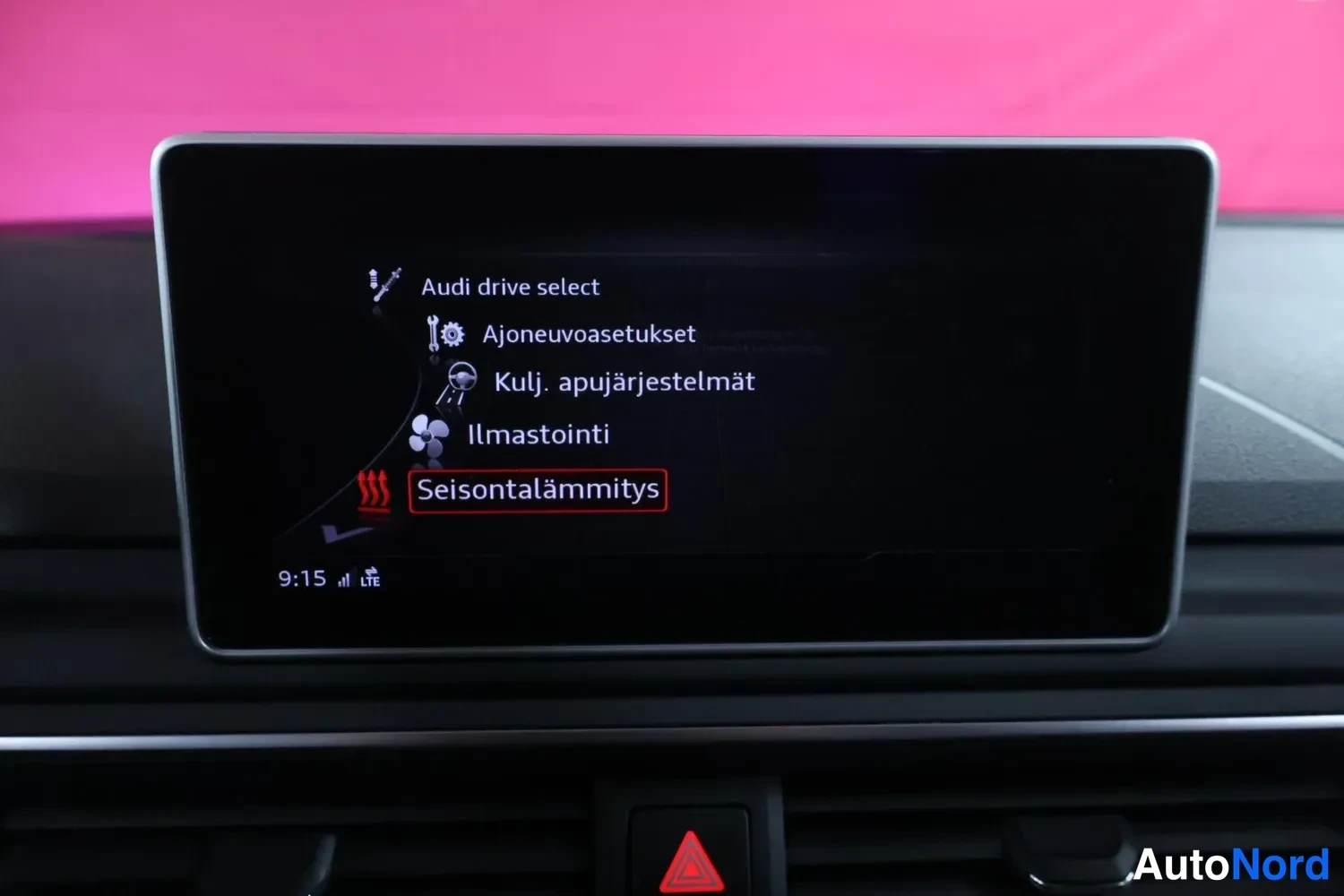Yksityiskohta: Audi-auton keskikonsolin infotainment-näyttö valikossa, jossa valittuna Seisontalämmitys; listalla myös Audi drive select, Ajoneuvoasetukset, Kulj. apujärjestel
