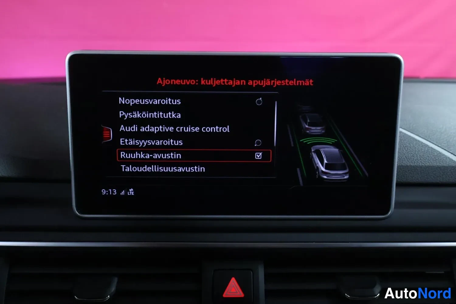 Yksityiskohta: Audi-auton infotainment-näyttö valikossa 'Ajoneuvo: kuljettajan apujärjestelmät' ruuhka-avustin valittuna; listalla mm. Audi adaptive cruise control, pysäköinti