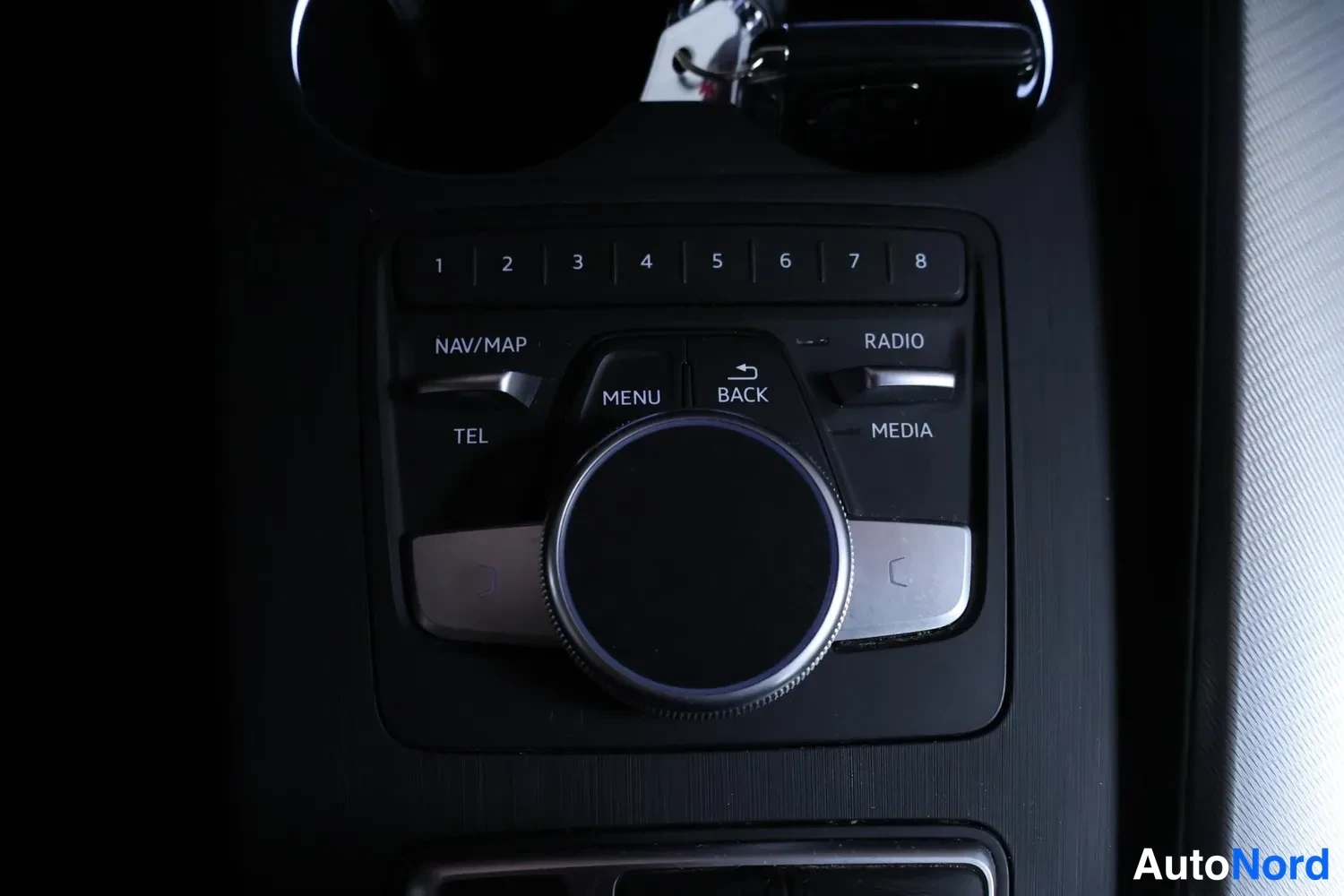 Yksityiskohta: Audi A4 Allroadin keskikonsolin MMI-ohjauspyörä ympärillään numeronäppäimet 1–8 sekä NAV/MAP, RADIO, TEL, MEDIA, MENU ja BACK -painikkeet.