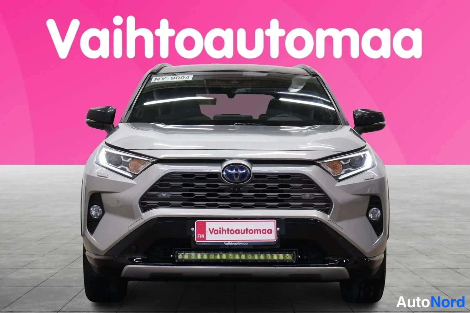 Edestä: Hopeanharmaa Toyota RAV4 suoraan edestä, maski, Toyota-merkki, ajovalot ja öljytyystöykkä näkyvissä.
