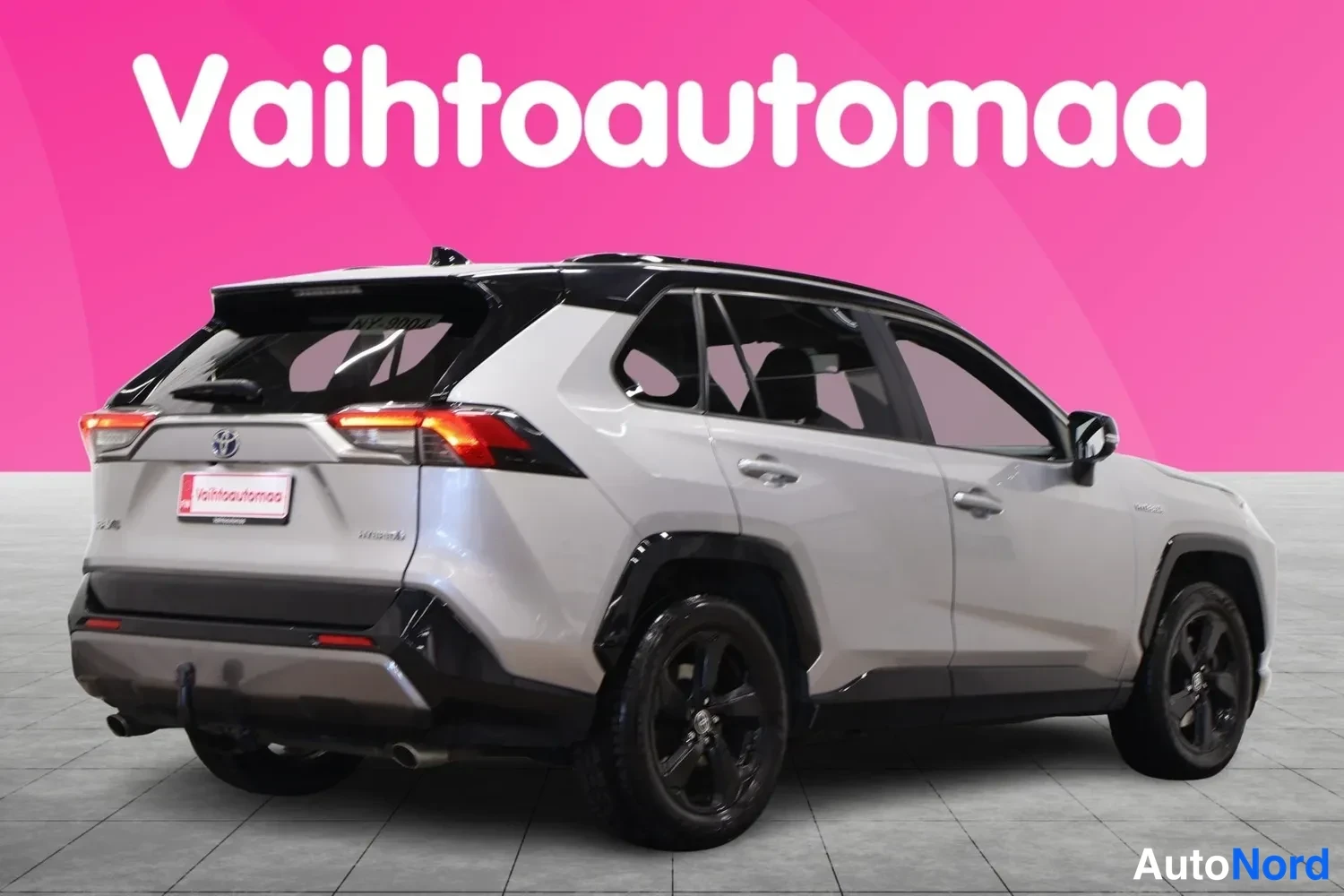 Takaviisto: Toyota RAV4 takakulmanäkyvissä vasemmalta, hopeanharmaa kori, mustat vanteet ja vetokoukku.