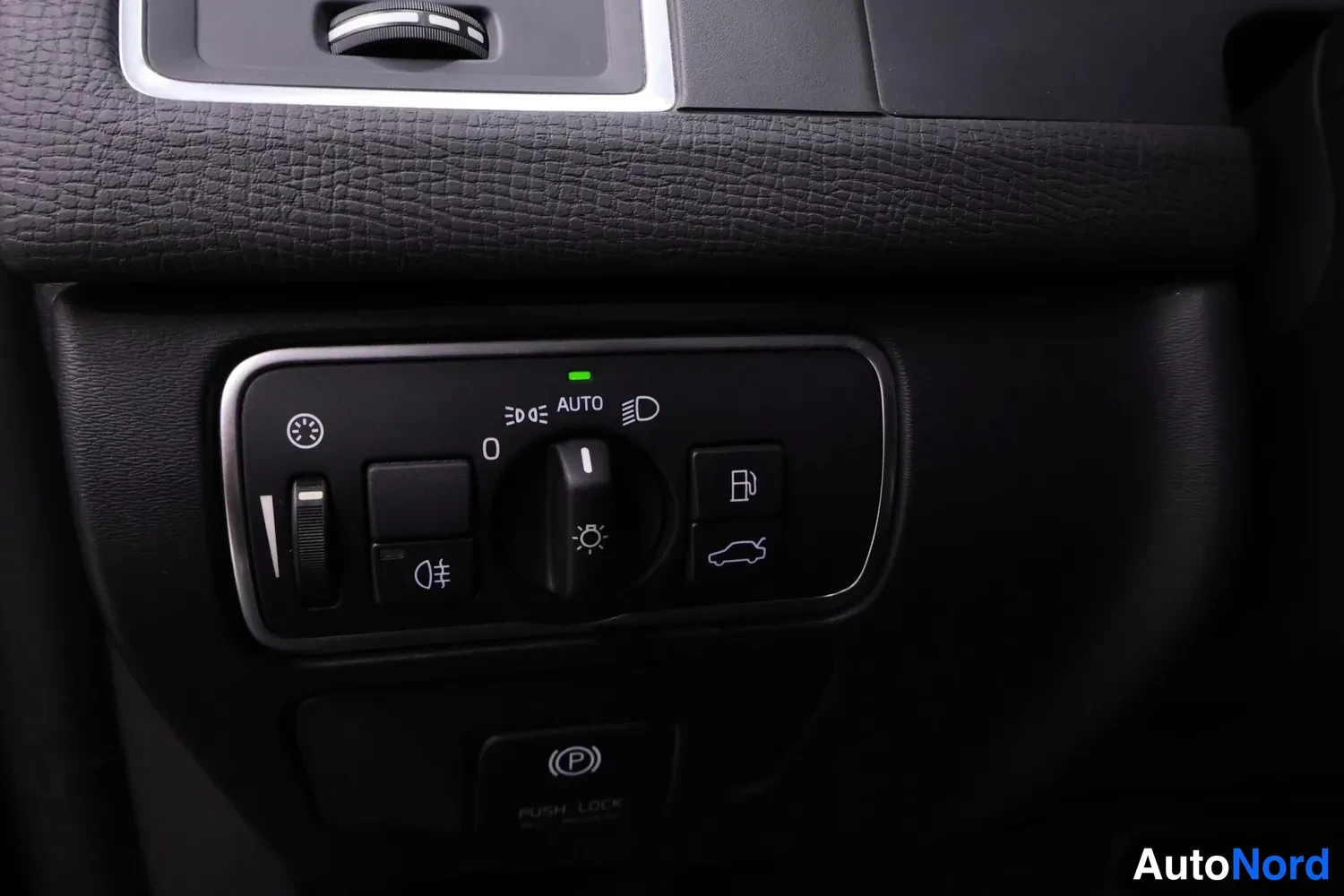 Muu: Valokytkimen tavaramerkki paneelissa AUTO-merkinnällä ja sähköisen seisontijarrun PUSH LOCK-painike.