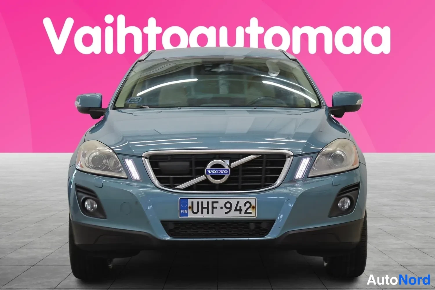 Edestä: Sininen henkilöauto suoraan edestä kuvattuna, rekisteritunnus, etusäleikkö ja ajovalot näkyvissä.