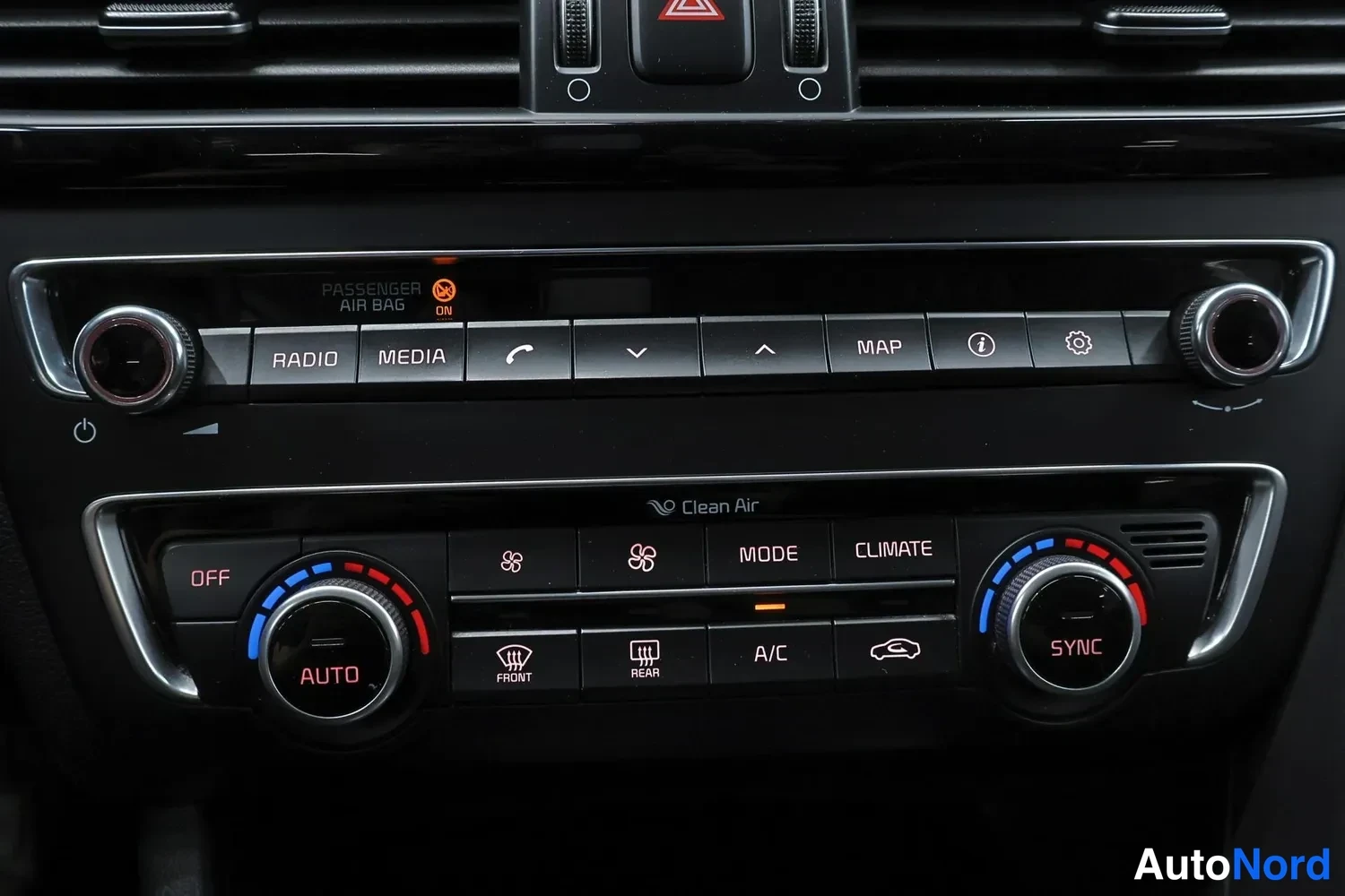 Muu: Auton kojelaudan keskikäyttöpaneeli: radio-, media- ja karttanapit sekä kaksivyöhykeilmastointi, jossa CLEAN AIR-teksti, AUTO- ja SYNC-säätönupit ja A/C-nappi.