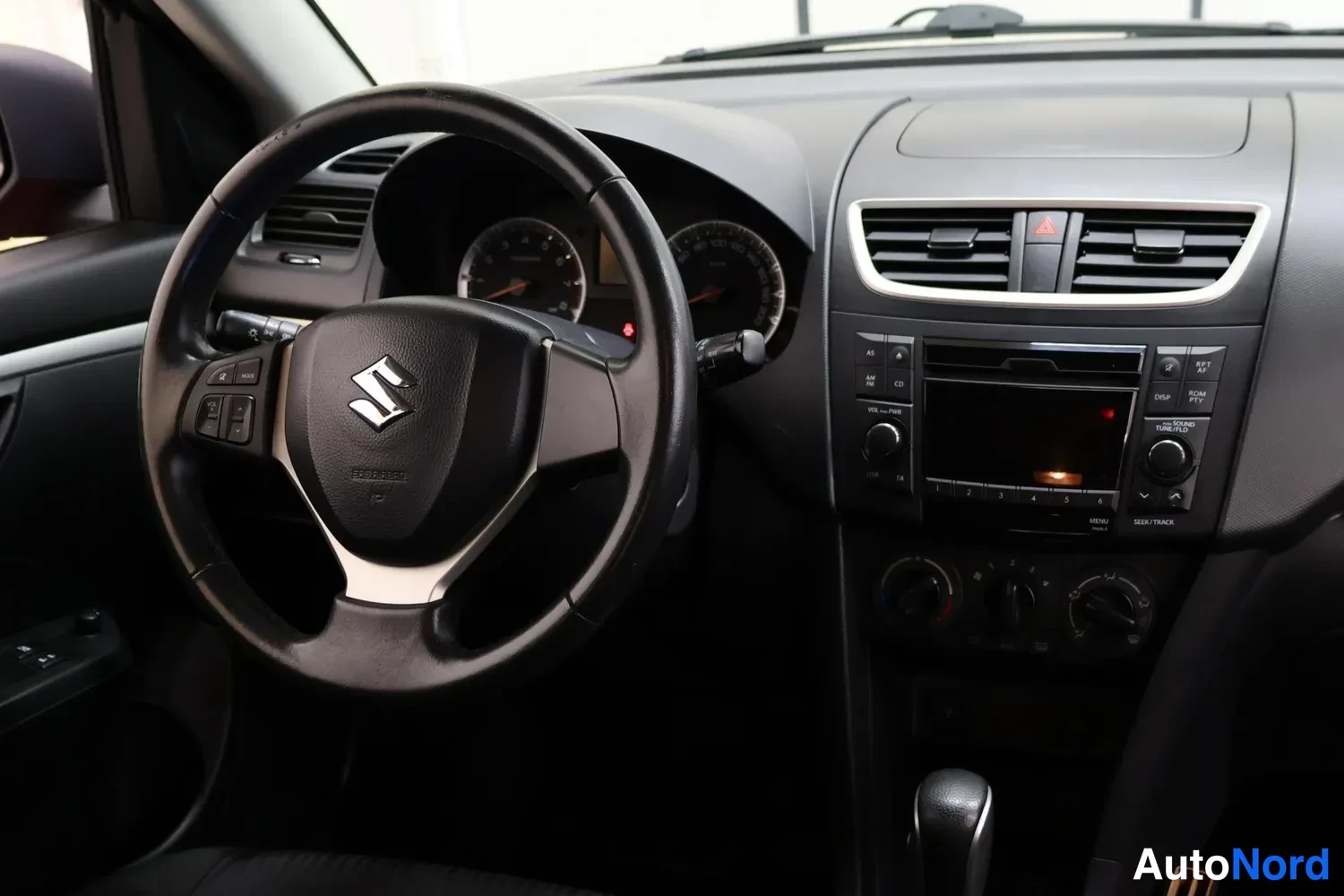 Yksityiskohta: Suzukin ohjaamon etuosaa: ratti, mittaristo, radio- ja ilmastointilaitteet sekä automaattivaihtajan vipu.