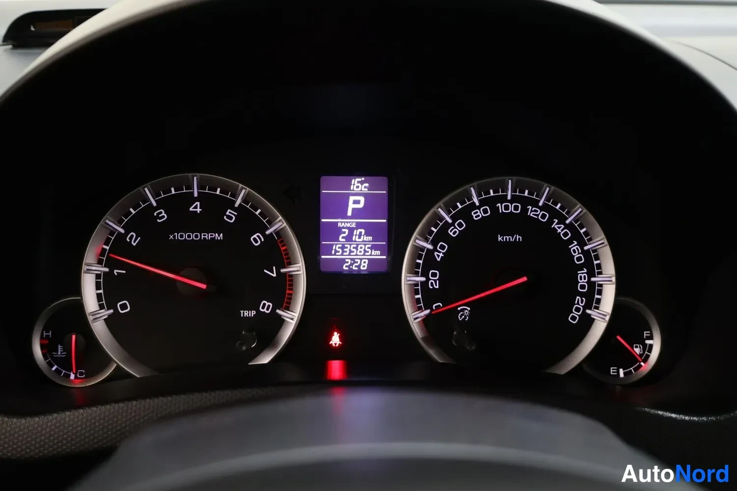 Muu: Suzuki Swiftin kojetaulun mittaristo: nopeusmittari, kierroslukumittari, polttoainemittari ja jäähdytinnesteen lämpömittari; näytöllä lukema 153585 km ja vaihde