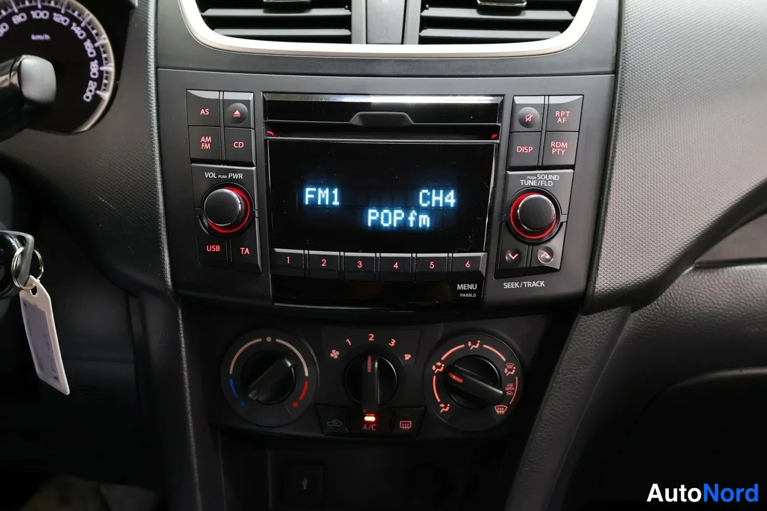 Muu: Suzuki Swiftin keskihalytysi radiopaneeli lähikuvassa: FM1 CH4 POPfm näytöllä, CD-asema, USB-liitin ja manuaaliset ilmastointisäätimet.