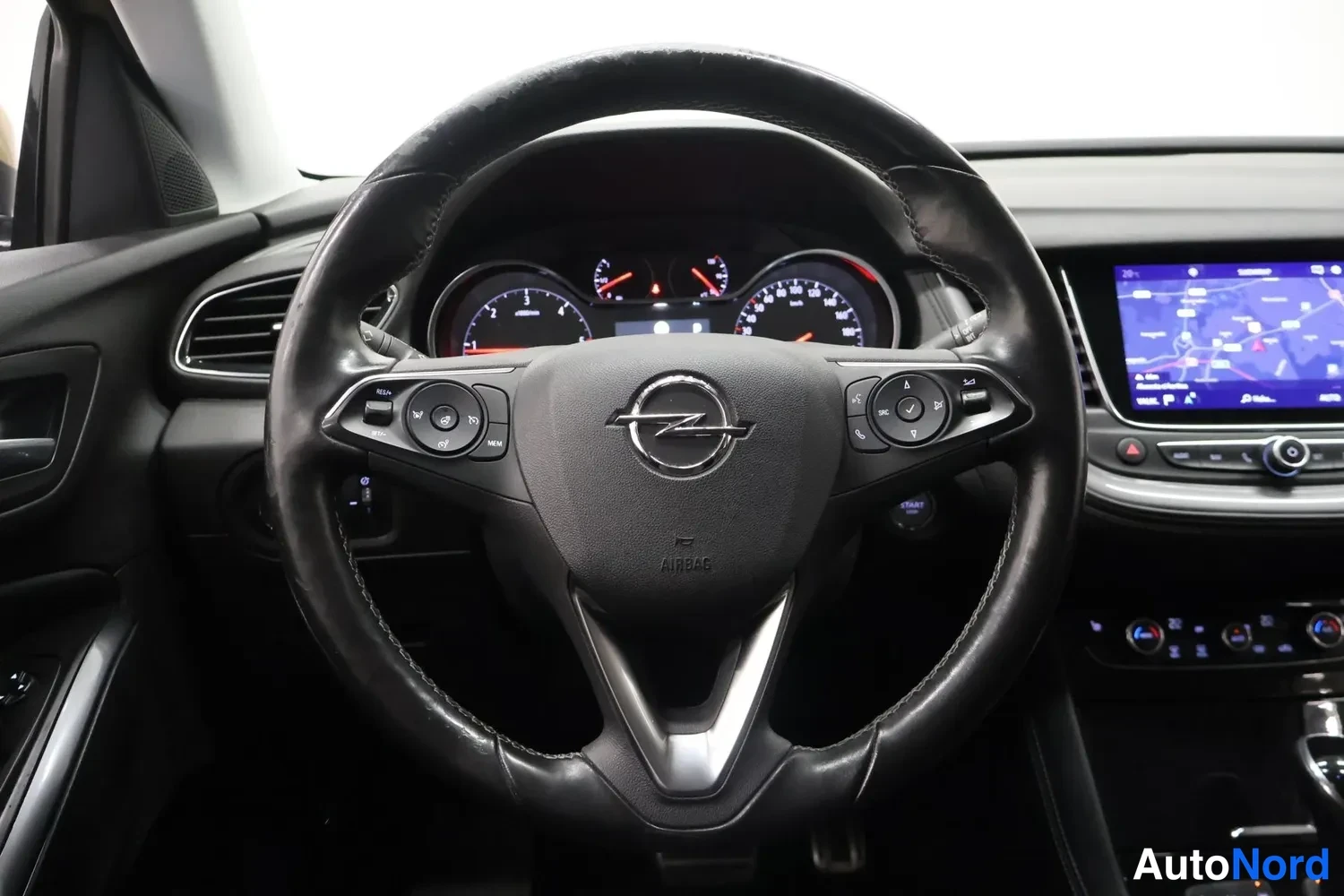 Muu: Opel-ohjauspyörä lähikuvassa: AIRBAG-teksti keskustaissa, monitoiminapit molemmin puolin ja mallipaneelin navigaationäyttö oikealla.