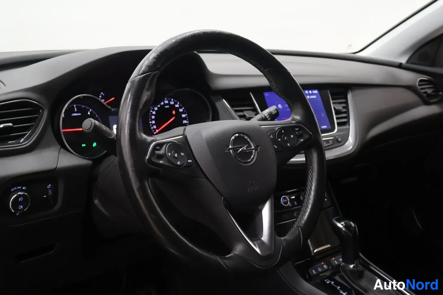 Muu: Ohjaamon näkymä kuljettajan puolelta: Opel-merkillä varustettu ohjauspyörä, mittaristo ja kosketusnäyttö-radiopaneeli näkyvät.