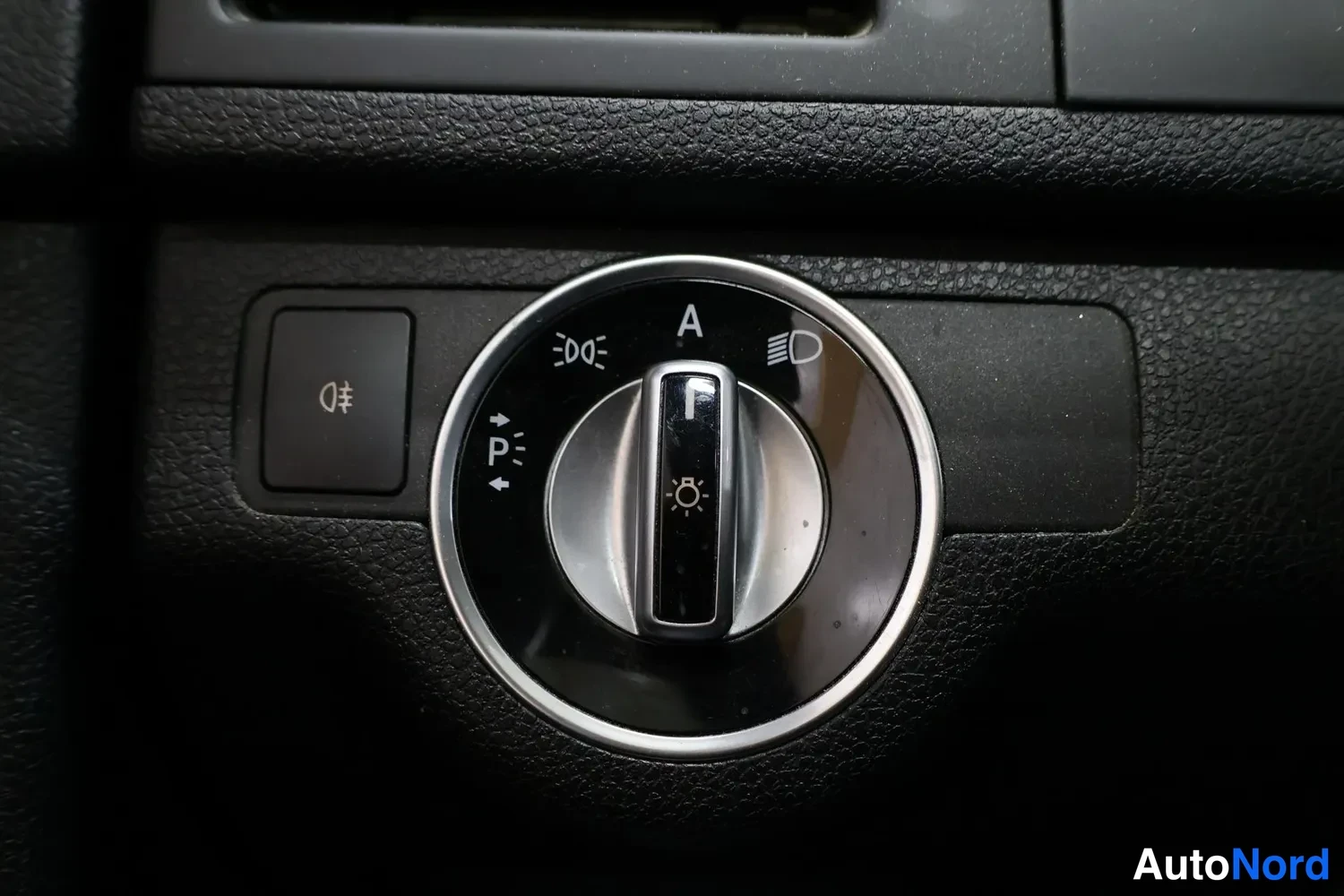 Yksityiskohta: Tarkkakuva Mercedes-Benzin valokytkimestä keskikonsolissa, jossa on asennot Auto, Park valot ja sumuvalot.