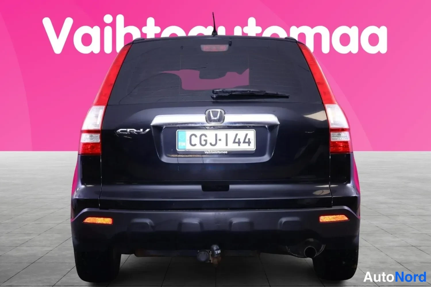 Takaa: Musta Honda CR-V suoraan takaa, pinkki tausta.