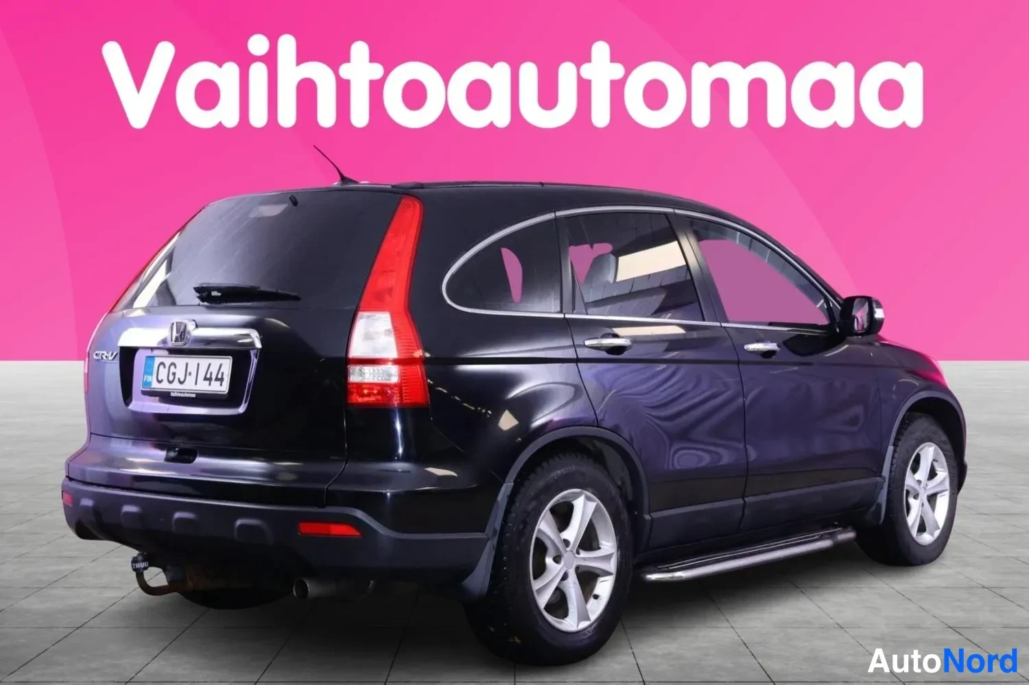 Takaviisto: Musta Honda CR-V takaviistosta vasemmalta, valoisa pinkki tausta.