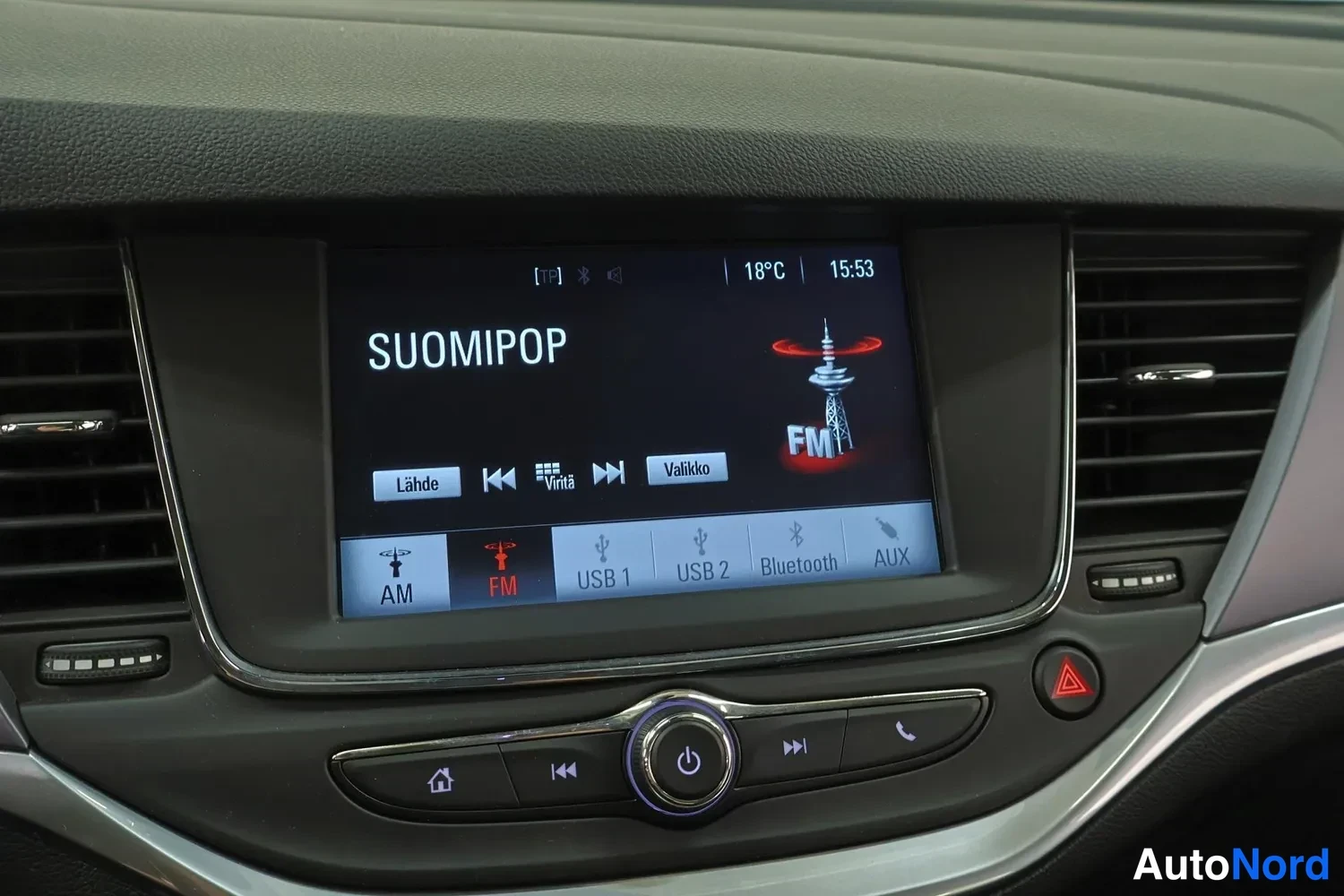 Muu: Kojelaudan radio- ja multimedianäyttö, jolla on käynnissä FM-kanava SUOMIPOP, lämpötila 18 °C ja kello 15:53, alareunassa AM, FM, USB 1, USB 2, Bluetooth ja AUX