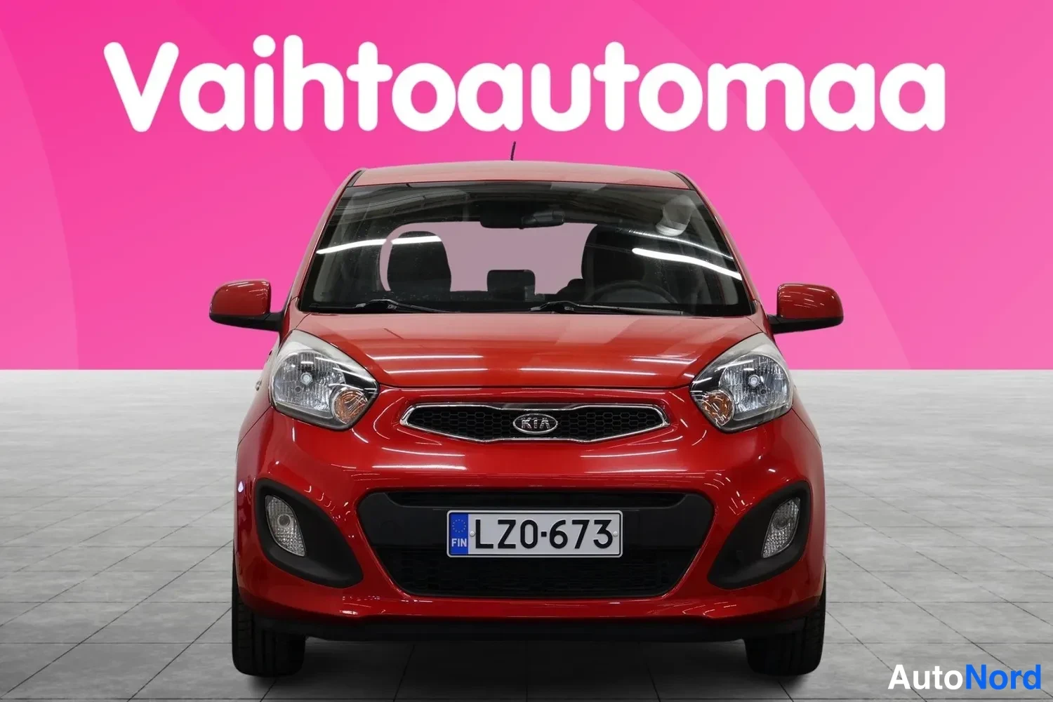 Edestä: Punainen Kia Picanto suoraan edestä, etusäleikkö ja KIA-merkki näkyvät.