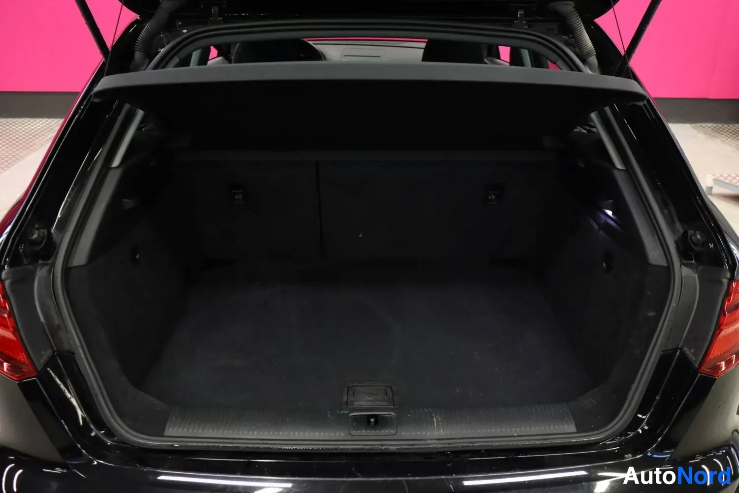 Takaa: Audi A3 Sportbackin auki nostettu takaluukku ja tyhjä tumma tavaratila kuvattuna suoraan takaa.
