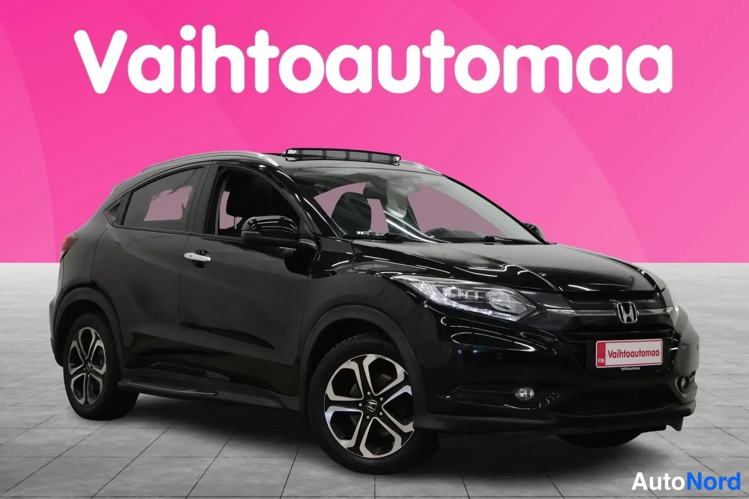 Etuviisto, nokka oikealle: Mustan Honda HR-V:n etunurkkakuva vasemmalta, etusäleikkö ja etupyörät näkyvät pinkillä taustalla.