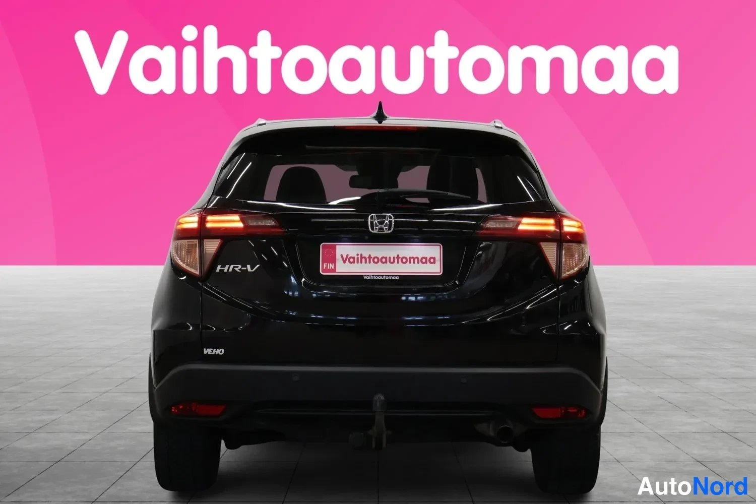 Takaa: Mustan auton takaosa suoraan takaa: takavalot, Honda-merkki ja perävaunun kytkin puskurissa.