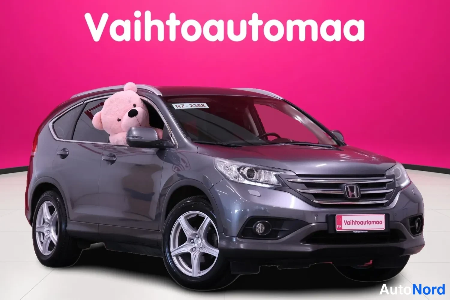 Etuviisto, nokka oikealle: Tummanharmaa Honda CR-V etuviistosta oikealta studiotaustaa vasten. Kattokaiteet, sumuvalo ja kevytmetallivanteet näkyvät; kuljettajan ikkunassa vaaleanp