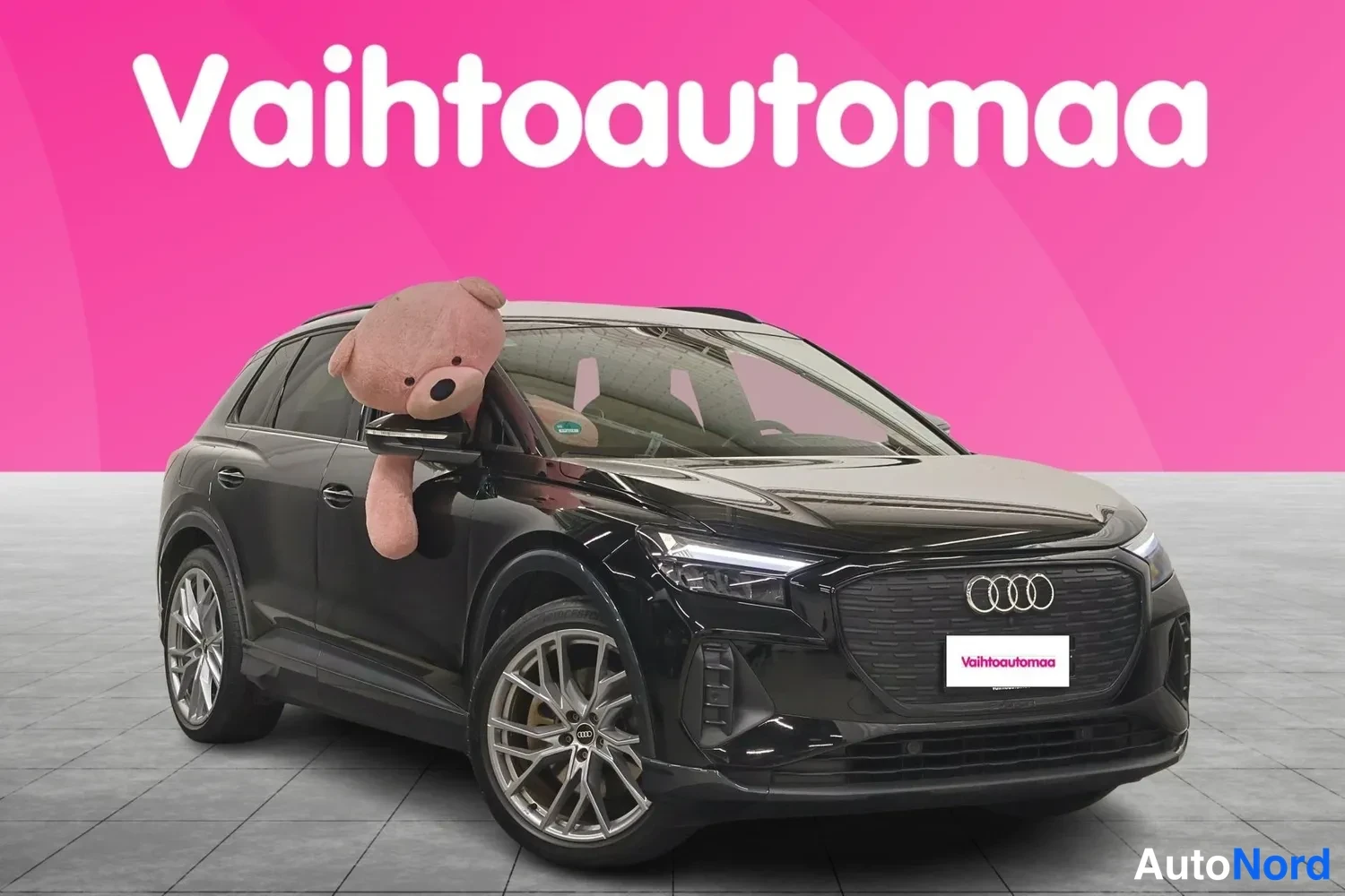 Etuviisto, nokka oikealle: Musta Audi Q4 e-tron -maasturi kolmessa neljäsosassa edestä oikealta, nallekarkki peiliin nojaa
